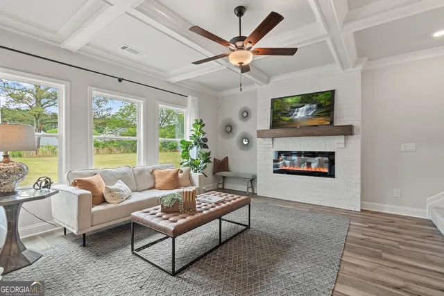 a living room with furniture and a large window with kitchen view