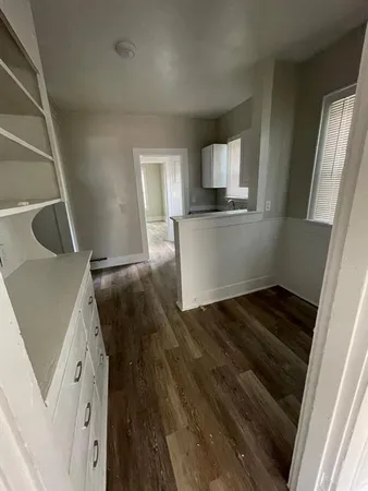 a view of kitchen and empty room with wooden floor