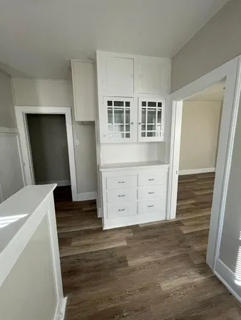 a view of an empty room with wooden floor and cabinet