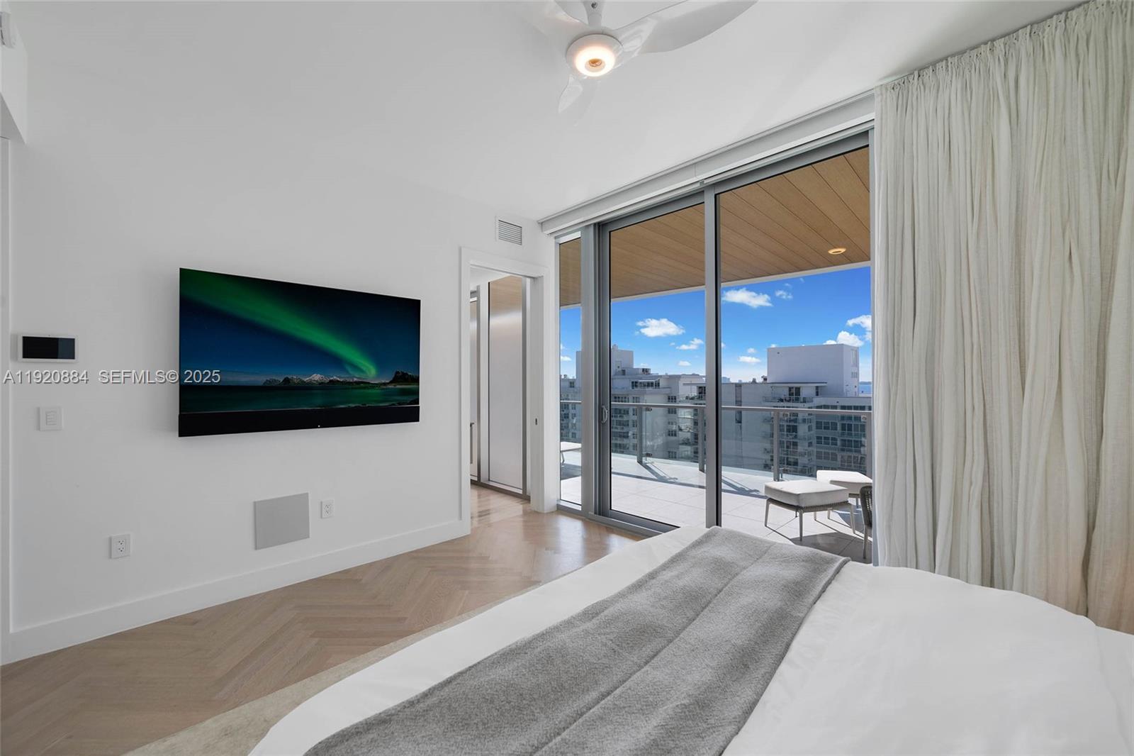 5775 Collins Avenue, Unit 1501 Miami Beach, FL 33140 - Photo 40 of 77 a living room with a flat screen tv and a floor to ceiling window