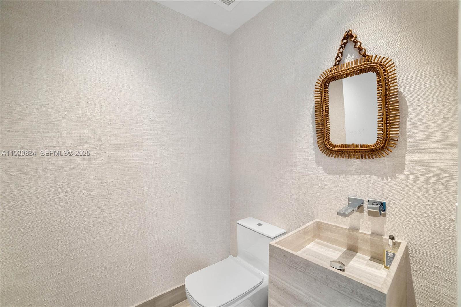5775 Collins Avenue, Unit 1501 Miami Beach, FL 33140 - Photo 52 of 77 a bathroom with a toilet sink and mirror