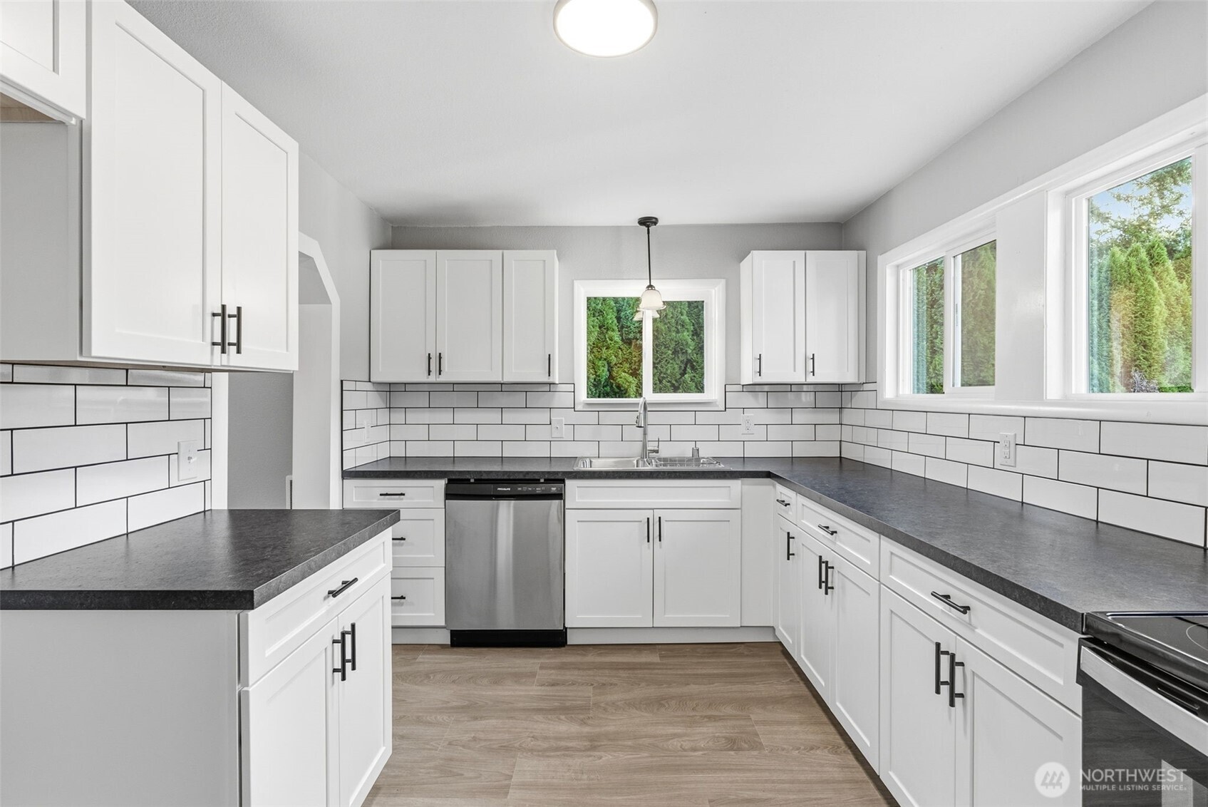 508 Nevada Drive Longview, WA 98632 - Photo 7 of 29 a kitchen with a sink dishwasher a stove and white cabinets with wooden floor