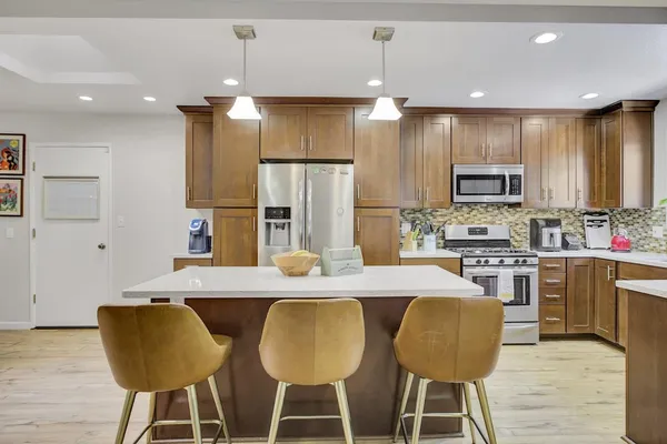 a kitchen with stainless steel appliances granite countertop a refrigerator a stove and a sink with wooden floor