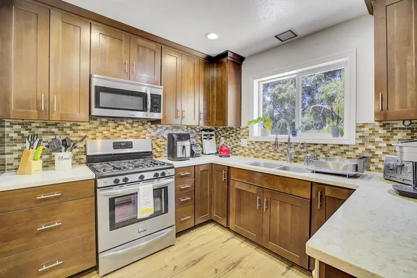 a kitchen with a sink a counter top space and living room view