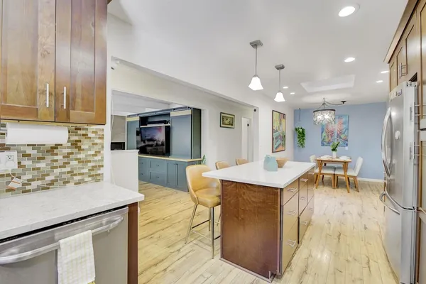 a dining room with furniture a kitchen view and wooden floor