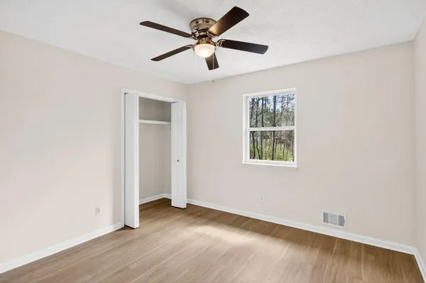 an empty room with wooden floor ceiling fan and windows