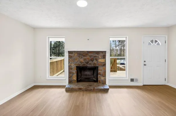 an empty room with windows and fireplace