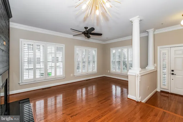a view of an empty room with window and wooden floor