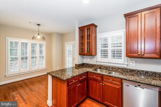 a kitchen with stainless steel appliances granite countertop wooden cabinets a sink and a large window