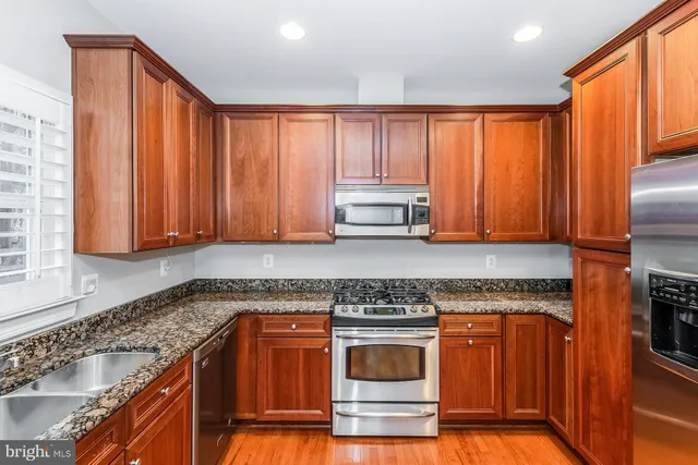 a kitchen with stainless steel appliances granite countertop a stove a sink and a microwave