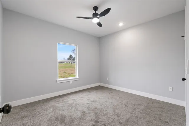 an empty room with a window and a ceiling fan