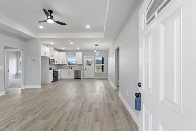 a view of a kitchen with a sink and dishwasher a refrigerator with wooden floor