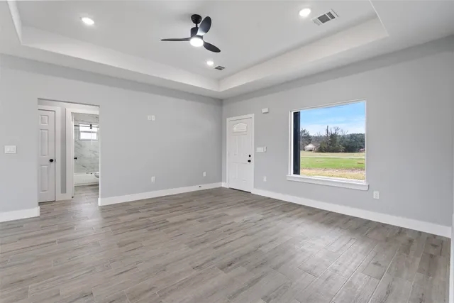 a view of an empty room with a window and wooden floor