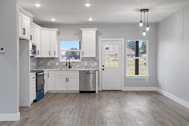 a kitchen with a sink cabinets stainless steel appliances and window