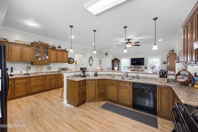 a large kitchen with stainless steel appliances kitchen island granite countertop a sink dishwasher a stove and a dining table with wooden floor