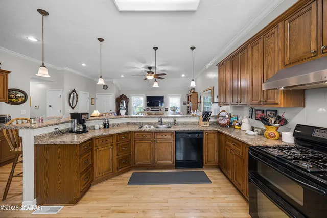 a kitchen with stainless steel appliances granite countertop a sink a stove and a wooden floors