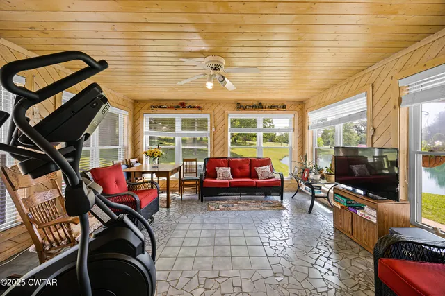 a living room with furniture a flat screen tv and floor to ceiling window