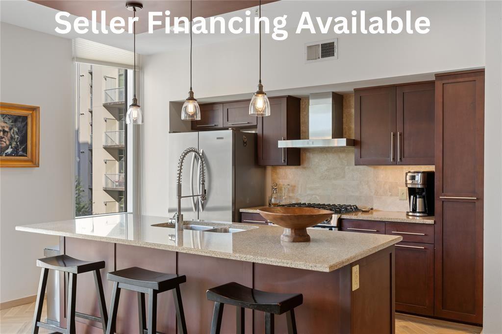 Kitchen with parquet flooring, light stone counters, a kitchen breakfast bar, and a kitchen island with sink