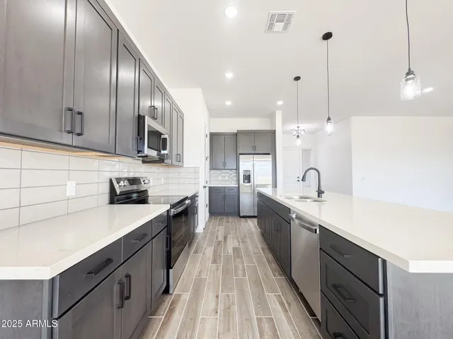 a large kitchen with stainless steel appliances sink a stove and cabinets
