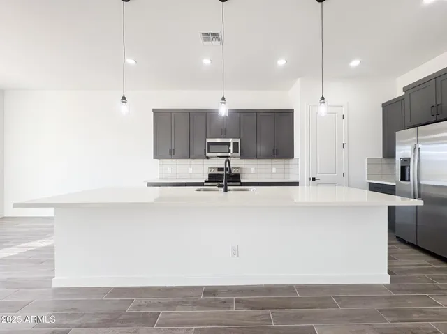 a view of kitchen with stainless steel appliances granite countertop a sink a oven and a refrigerator