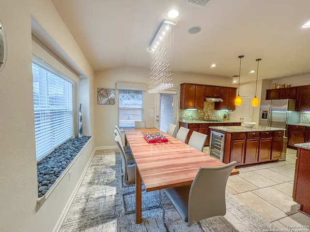 a open kitchen with stainless steel appliances kitchen island granite countertop a table chairs sink and cabinets