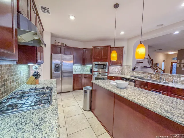a view of a kitchen with stainless steel appliances granite countertop a stove a sink a oven with a dining table and chairs