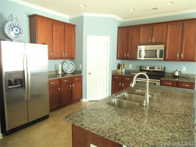 1006 Green Terra Road Indian Trail, NC 28079 - Photo 3 of 11 a kitchen with granite countertop a sink a stove and a wooden cabinets