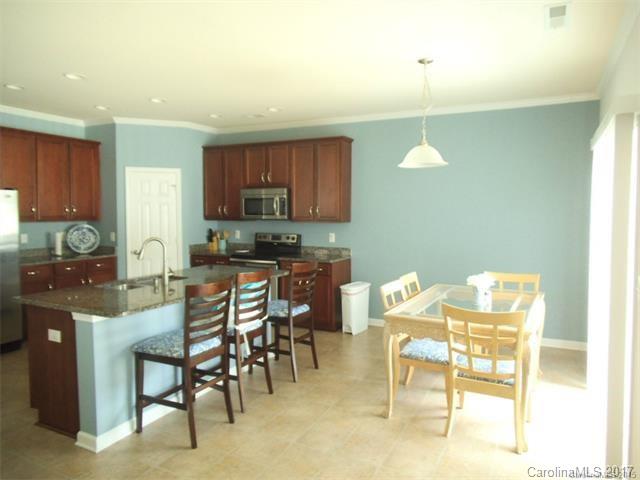 1006 Green Terra Road Indian Trail, NC 28079 - Photo 4 of 11 a kitchen with stainless steel appliances kitchen island granite countertop a table and chairs