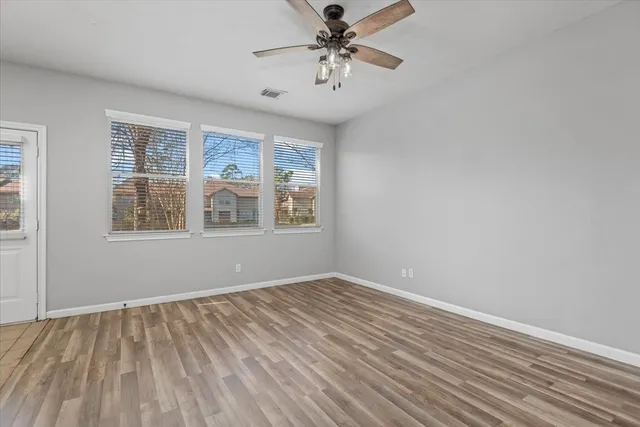 a view of an empty room with a window and wooden floor