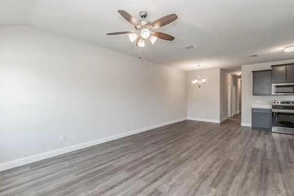 a view of an empty room with window and wooden floor