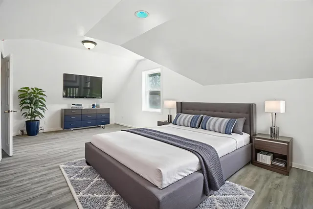 a spacious bedroom with a bed and a flat screen tv