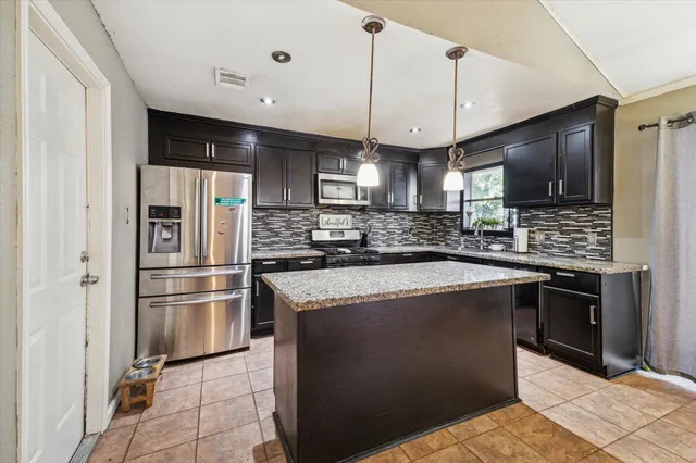 a kitchen with stainless steel appliances granite countertop a sink a stove a refrigerator and a oven