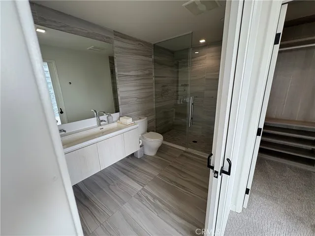 a bathroom with a sink a toilet a mirror and shower