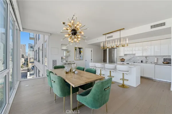 a view of a dining room and livingroom with furniture wooden floor a rug a painting and a chandelier