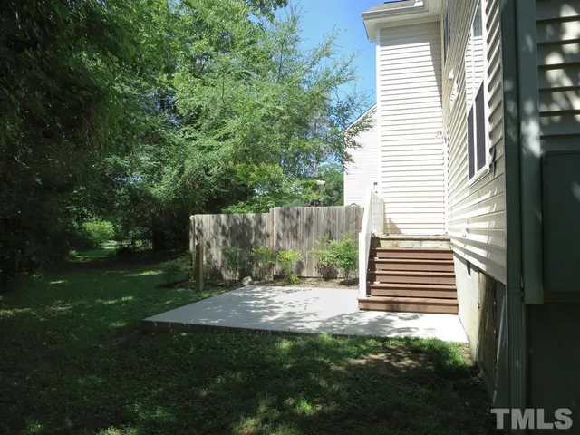 a backyard of a house with plants and large trees