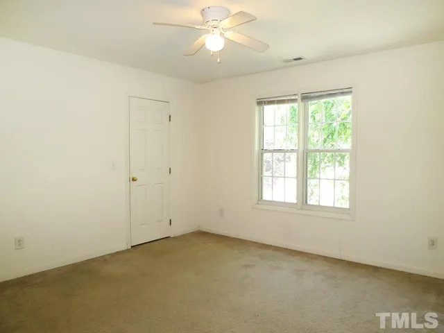 an empty room with a window and a fan