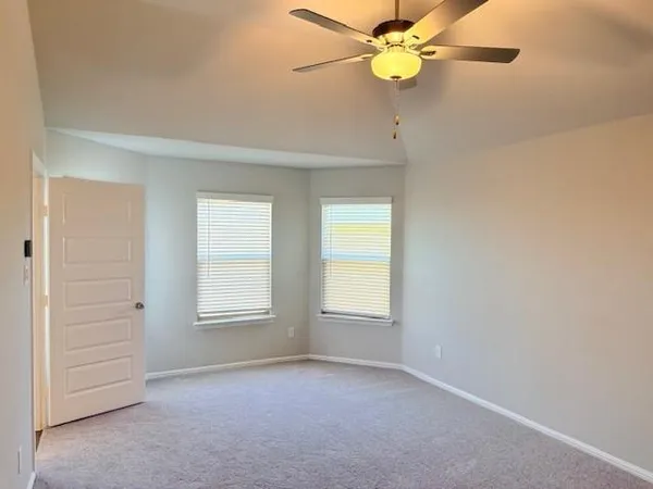 an empty room with windows and fan