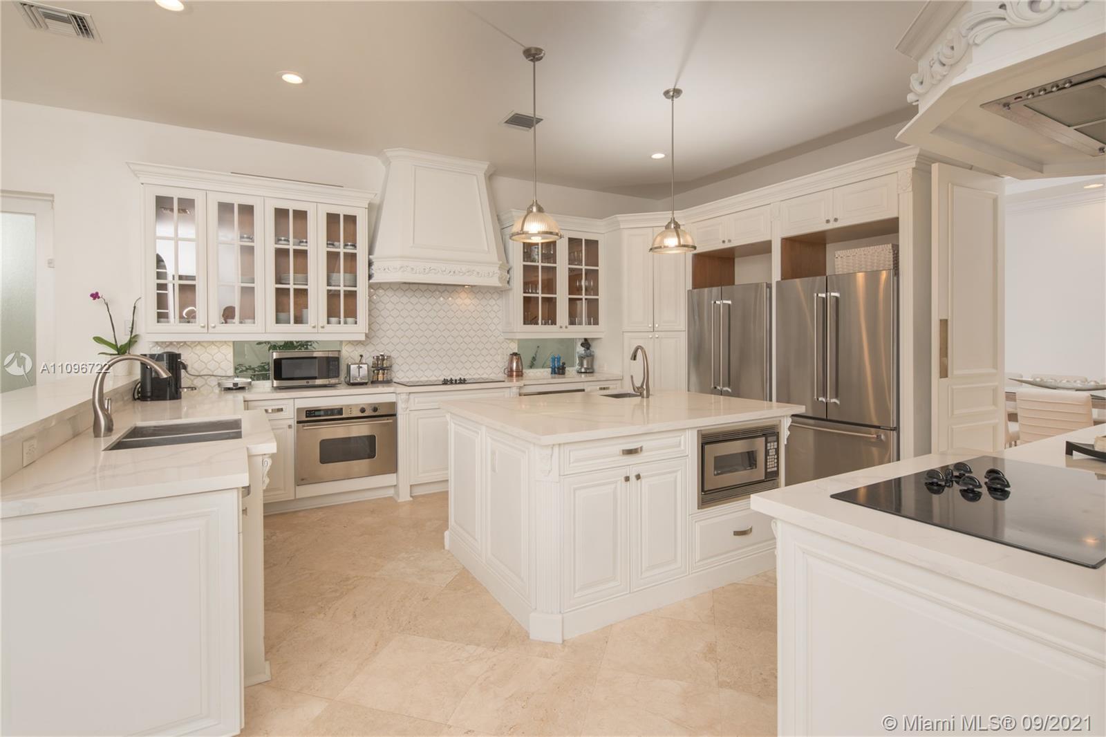 4900 Pine Tree Drive Miami Beach, FL 33140 - Photo 22 of 64 a kitchen with white cabinets and appliances