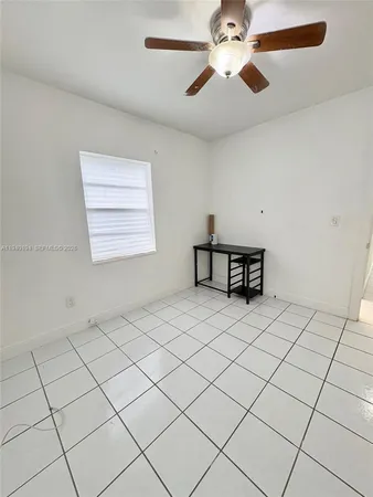 a living room with a table and a ceiling fan