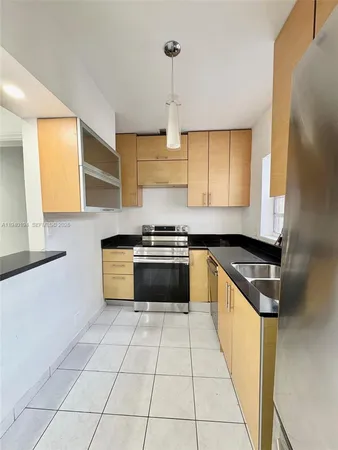 a kitchen with granite countertop a stove a sink and a refrigerator
