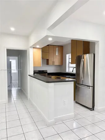 a kitchen with granite countertop a refrigerator and a stove top oven