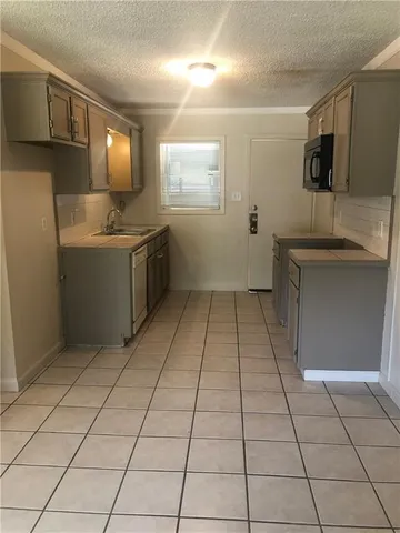 a kitchen with granite countertop a sink a stove top oven and cabinets