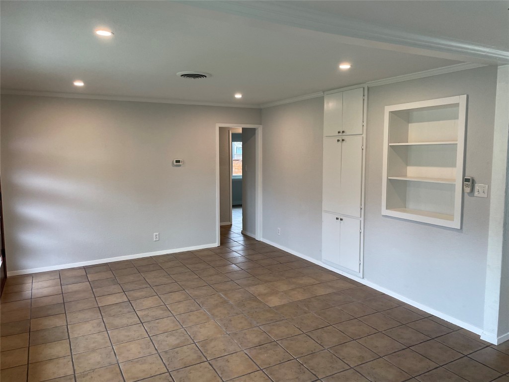4619 Jinx Avenue, Unit A Austin, TX 78745 - Photo 12 of 15 Unfurnished room with crown molding, built in features, recessed lighting, and dark tile patterned flooring