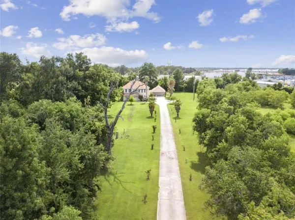 an aerial view of a house with swimming pool and large trees