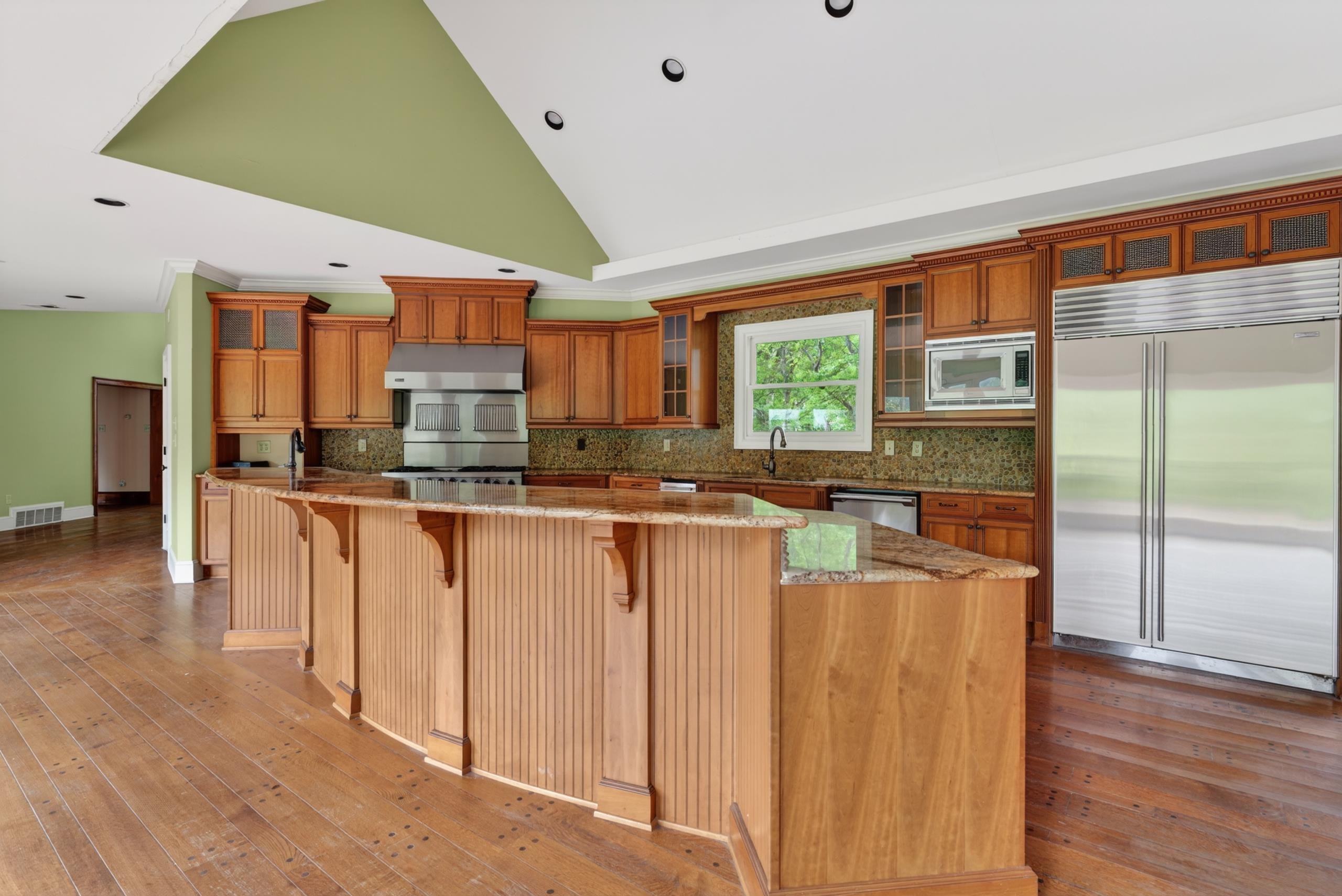 530 West Raines Road Memphis, TN 38109 - Photo 12 of 38 Expansive kitchen featuring a large curved island with wood paneling, wood-finish flooring, and a vaulted ceiling with recessed lighting
