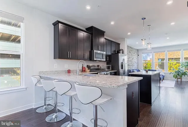 a kitchen with stainless steel appliances granite countertop a sink a stove a refrigerator cabinets and dining table