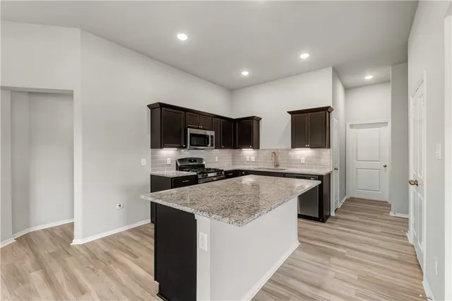 a large kitchen with a center island and stainless steel appliances