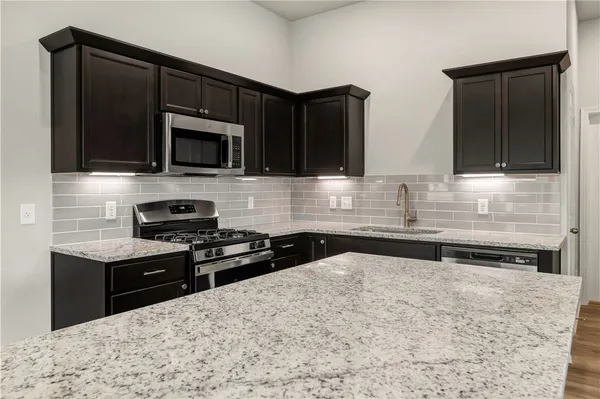 a kitchen with granite countertop a stove and a microwave