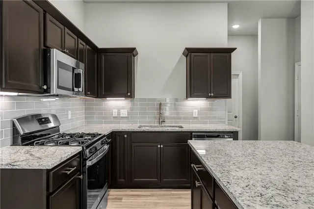 a kitchen with granite countertop kitchen island a sink stainless steel appliances and cabinets