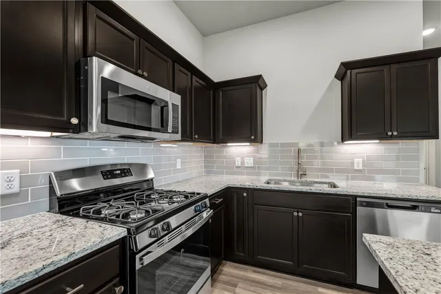 a kitchen with stainless steel appliances granite countertop a stove microwave and sink